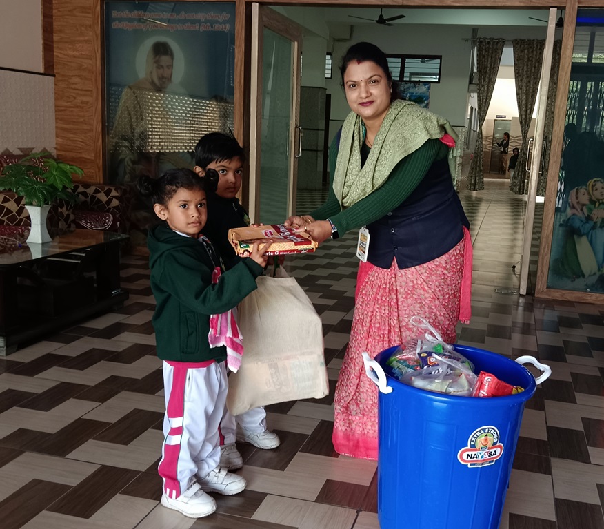 Children handing over a bag of provisions to a teacher during a collection drive