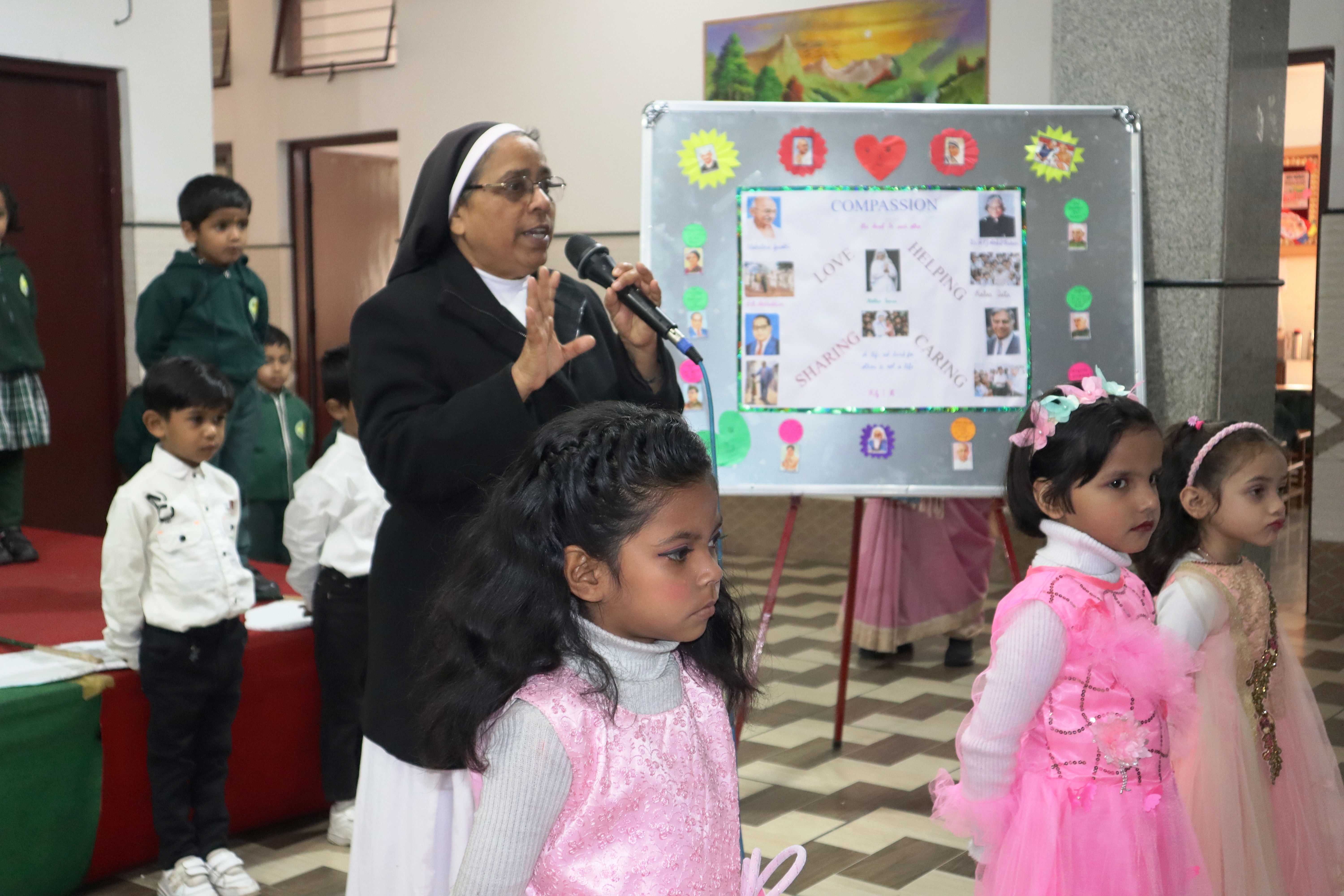 Sister addressing the children beside a compassion themed display board